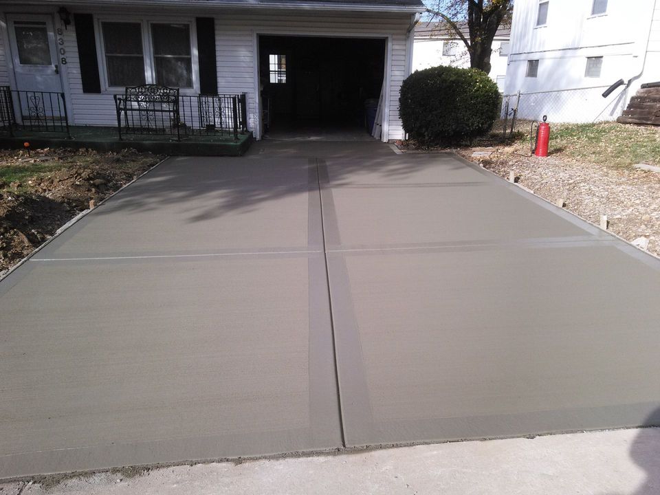 A concrete driveway is being built in front of a house.