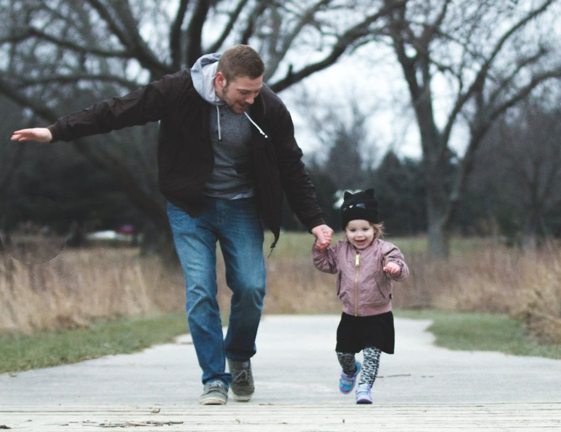 A man and a little girl are walking down a path.