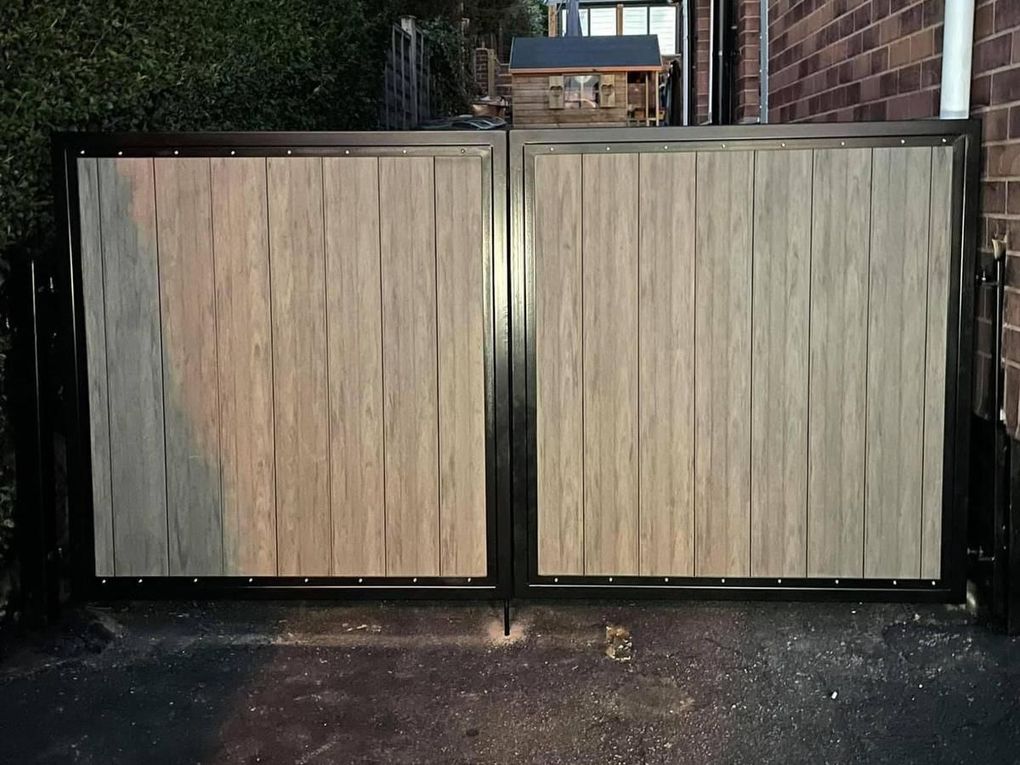Light grey wood-effect composite driveway gates in a black steel frame