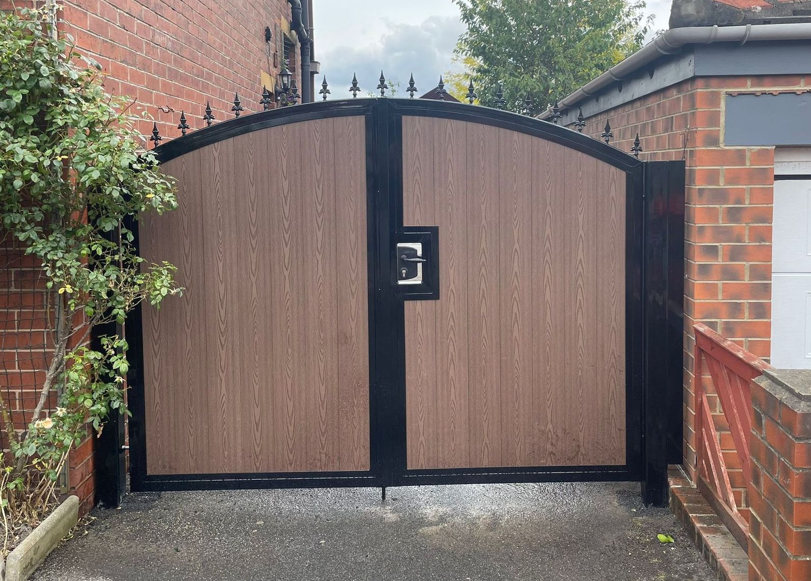 Arched composite driveway gates with fleur de lis top