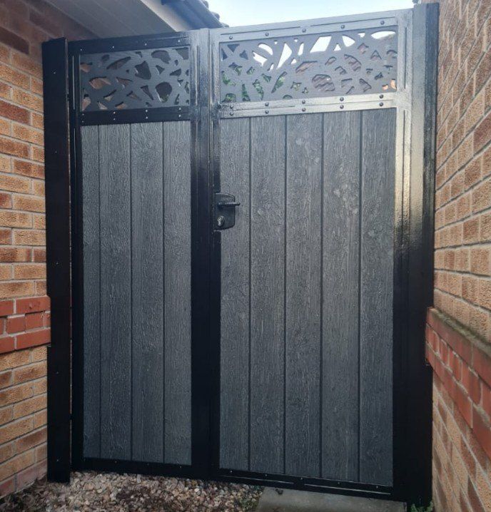 Black woodgrain composite double side gates, one narrow and one wide leaf, with laser-cut screen tops