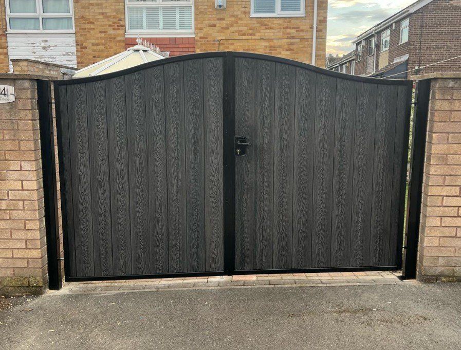 Black woodgrain composite driveway gates with an arched top and black steel frame