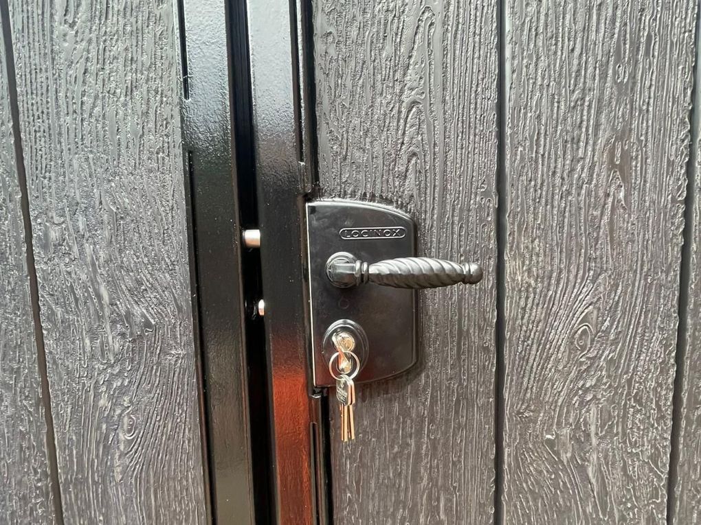 Close-up of a weather-rated locking handle and key barrel fitted to a composite gate