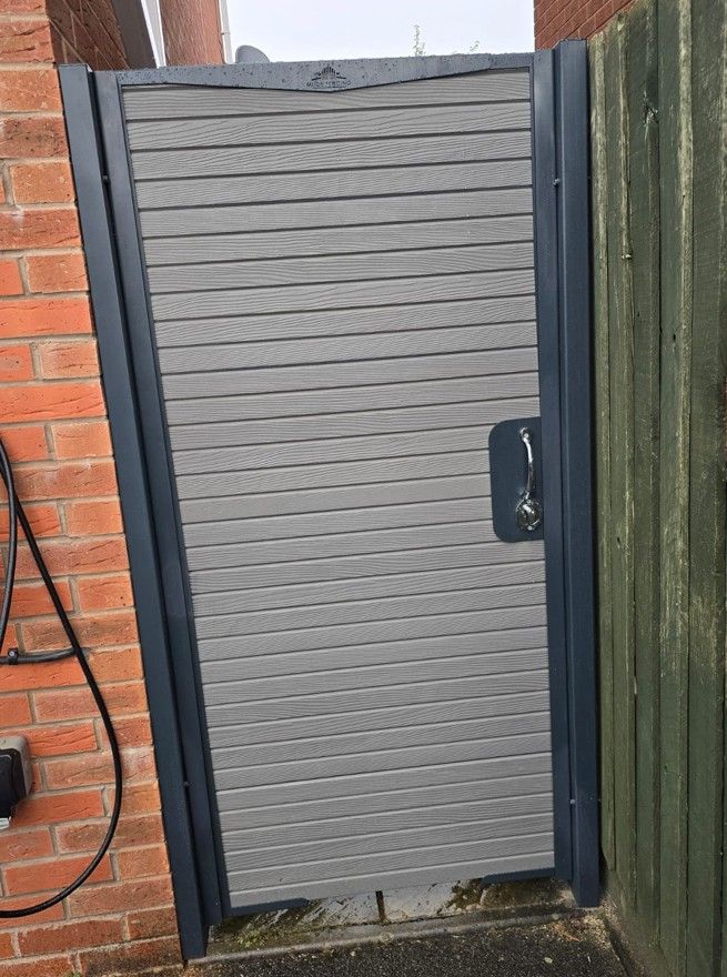 Light grey composite garden gate with horizontal boards between a wall and a fence