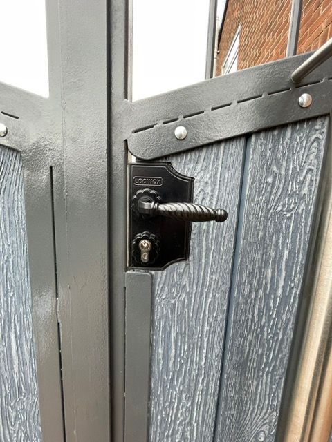 Close-up of a stainless steel pull handle and lock on a composite gate
