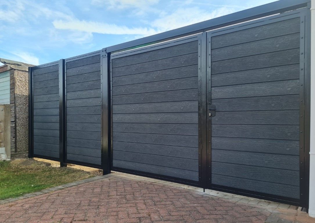 A black fence with a gate is sitting on top of a brick driveway.