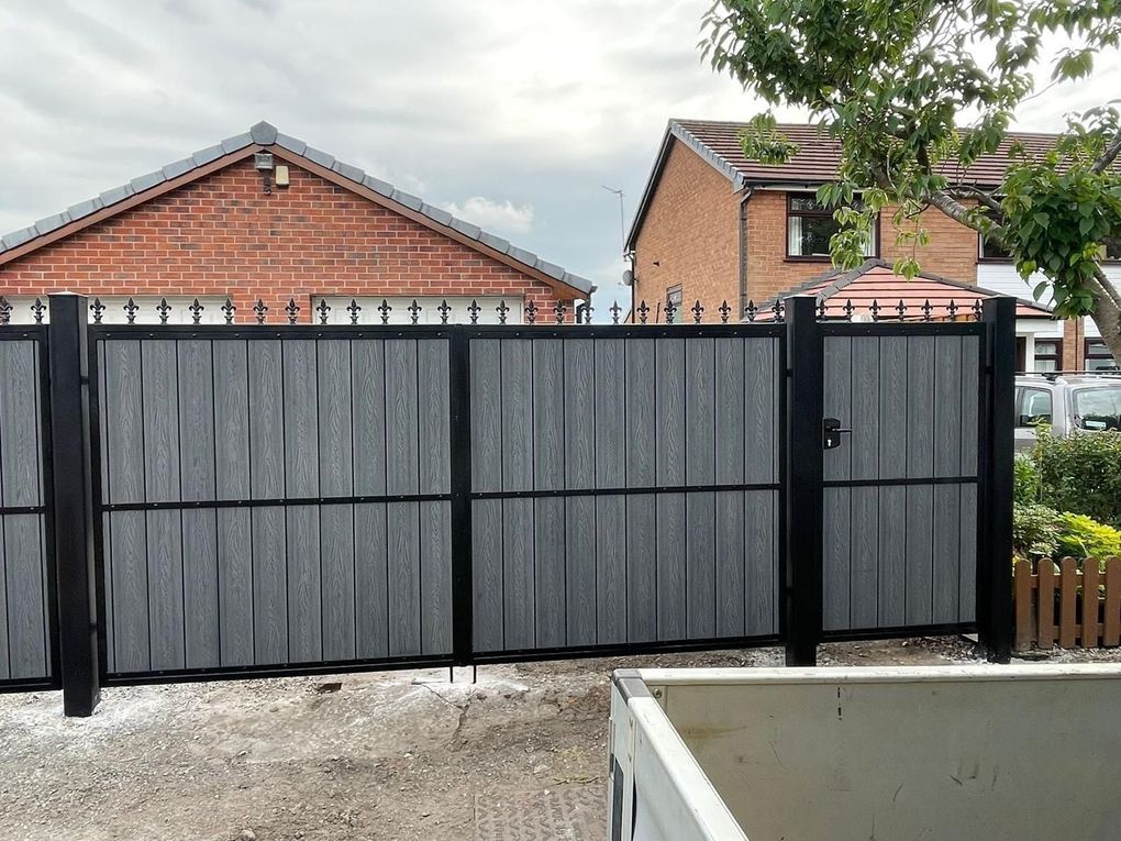 Grey woodgrain composite driveway gates and pedestrian gate with fleur-de-lis finials and a matching fence panel