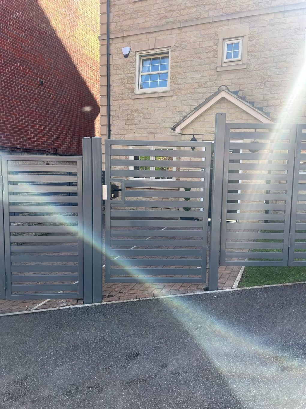 Grey powder-coated metal gate with horizontal slats, beside matching metal gates