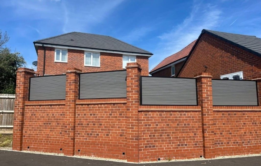 Composite Gates UK light grey composite fencing installed on a brick wall between brick pillars in Derby