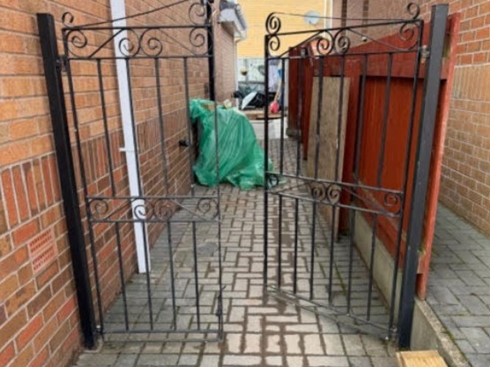 Metal scroll-top double gates fitted across a rear alley