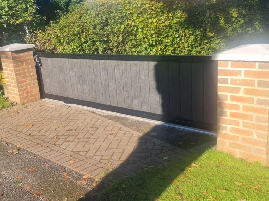 Composite sliding driveway gate part open beside a brick pier