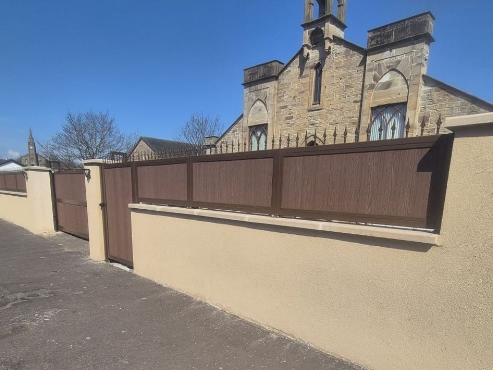 Walnut composite driveway gates with matching wall-top infill panels along a rendered boundary wall