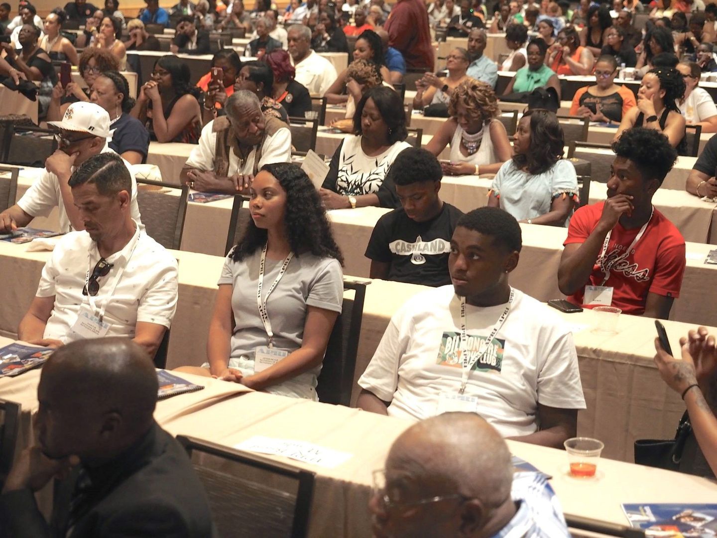 A large group of people are sitting at tables in a conference room.