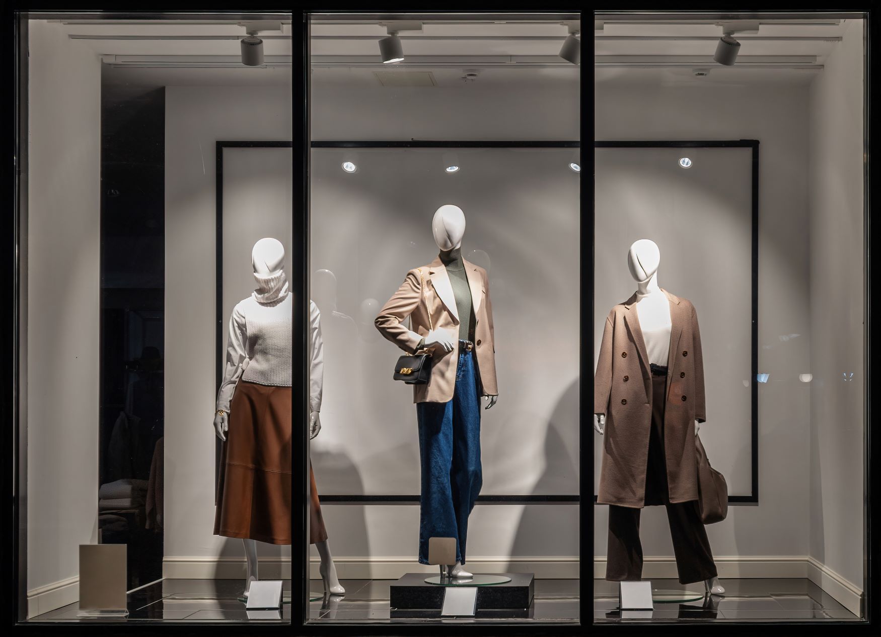 Three mannequins are displayed in a store window.