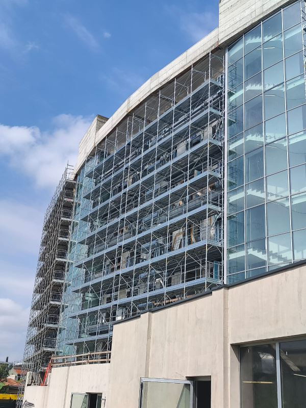 Moderno edificio per uffici in vetro con facciata curva sotto un cielo azzurro