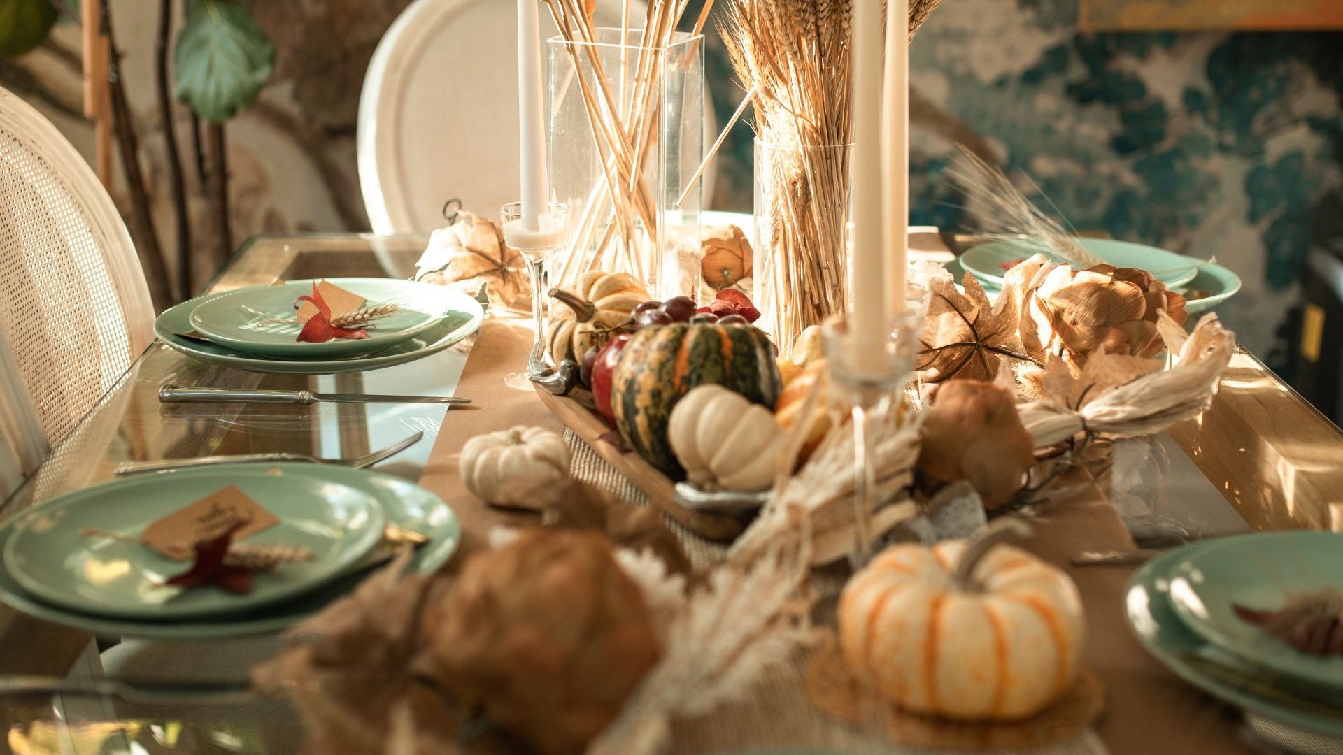 Elegant holiday dining table with warm seasonal decor and pumpkins.