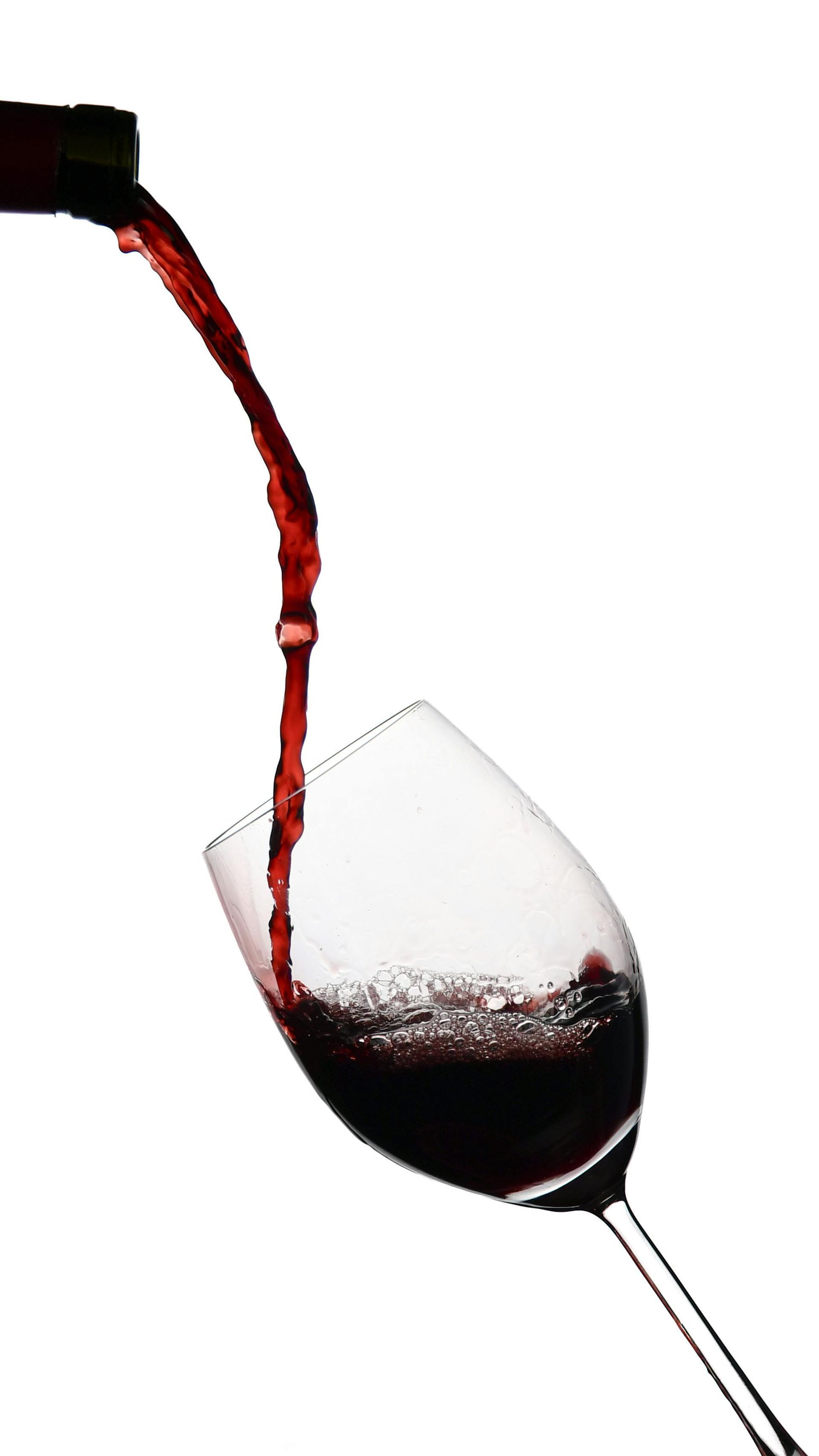 Vino rosso versato in un calice inclinato su sfondo bianco