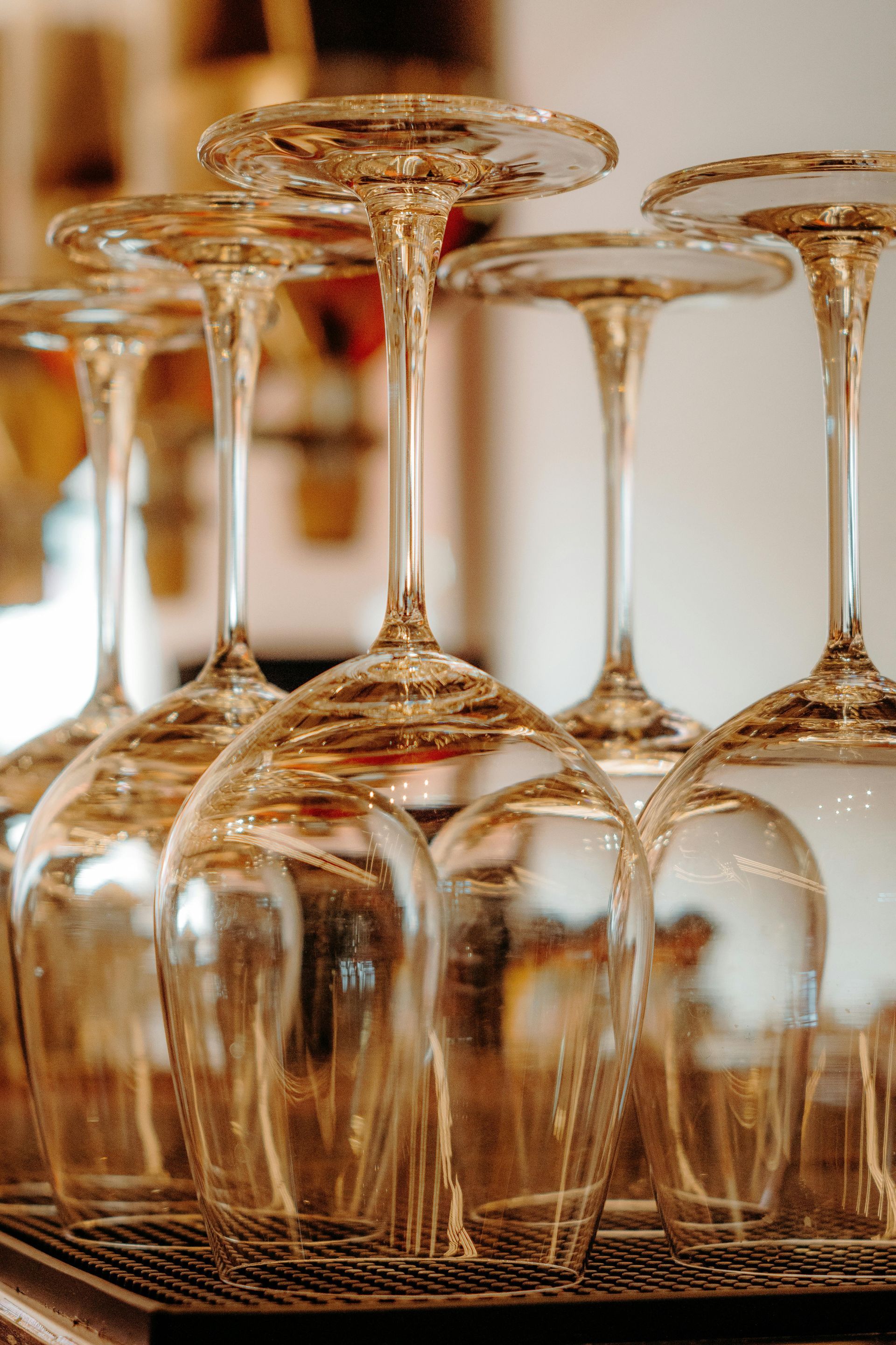 Calici da vino capovolti su un tavolo con riflessi caldi e uno sfondo sfocato