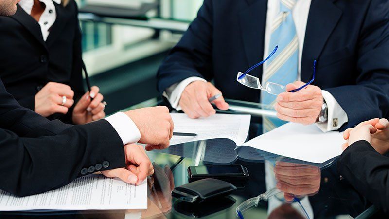 group of people discussing and gathered around paperwork