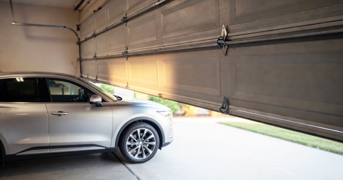 Silver SUV parked inside a garage with the door partially open, revealing daylight outside