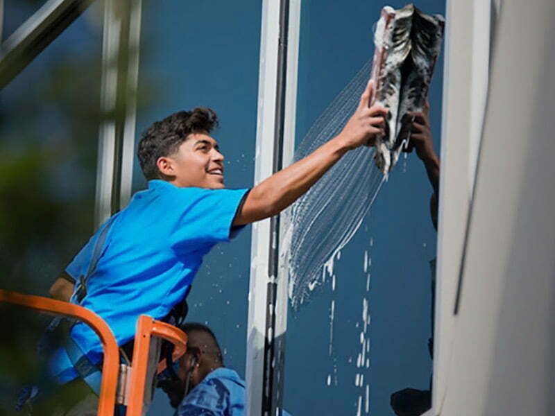 Window cleaner using a power washer on a house exterior