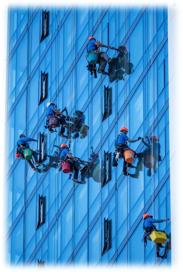 Window cleaner using a power washer on a house exterior