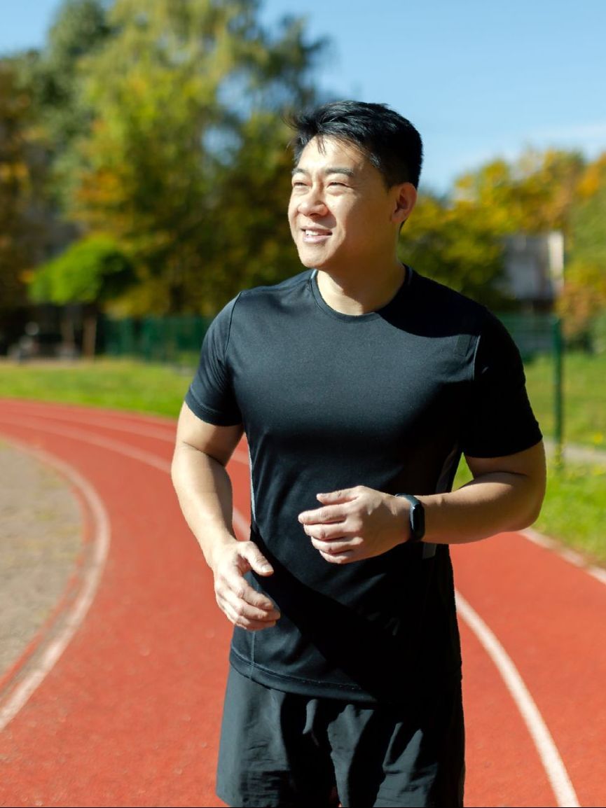 A man in a black shirt is running on a track