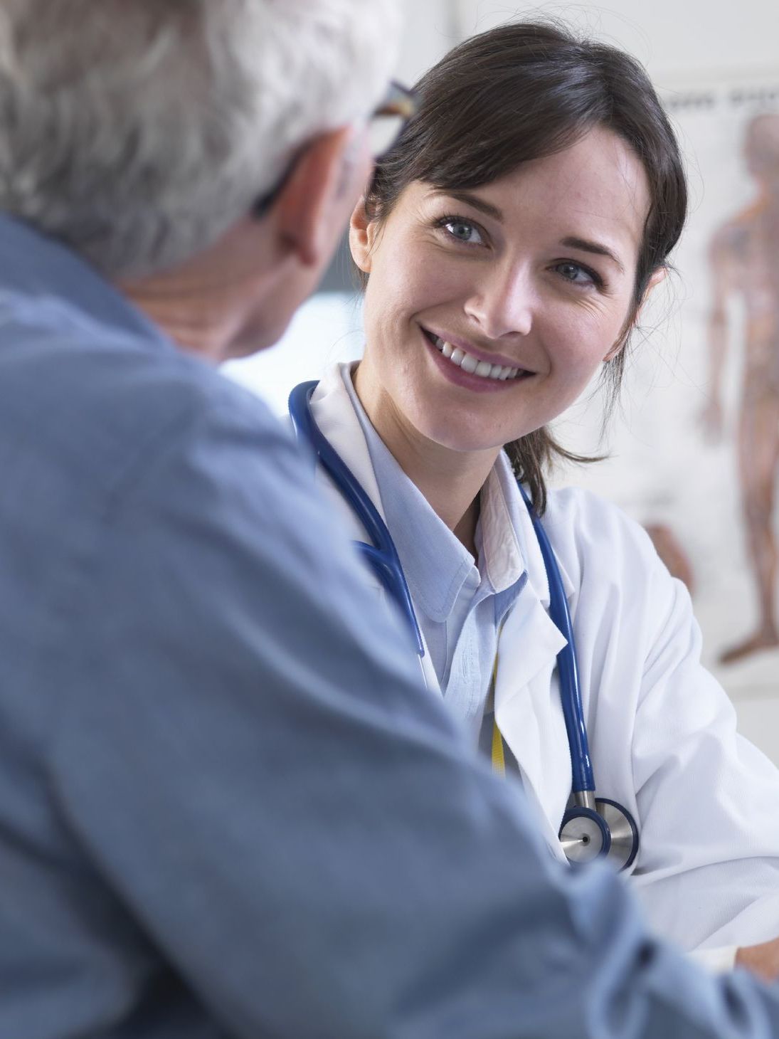 A female doctor is smiling while talking to an older man.