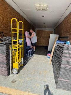 A man is loading a pink couch into a moving truck.