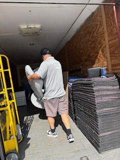 A man is carrying a chair into a moving truck.