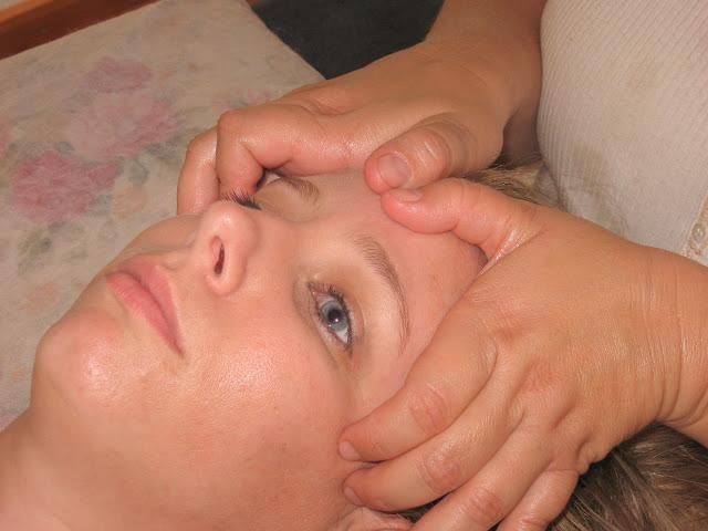 Hands massaging a person's temples while they lie on a pillow with eyes open