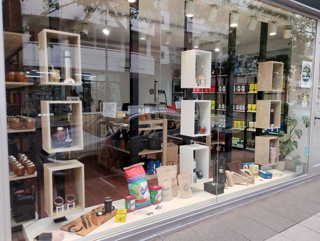 Exhibición en el escaparate de productos en cajas y artículos pequeños detrás de un cristal, con reflejos en la ventana.