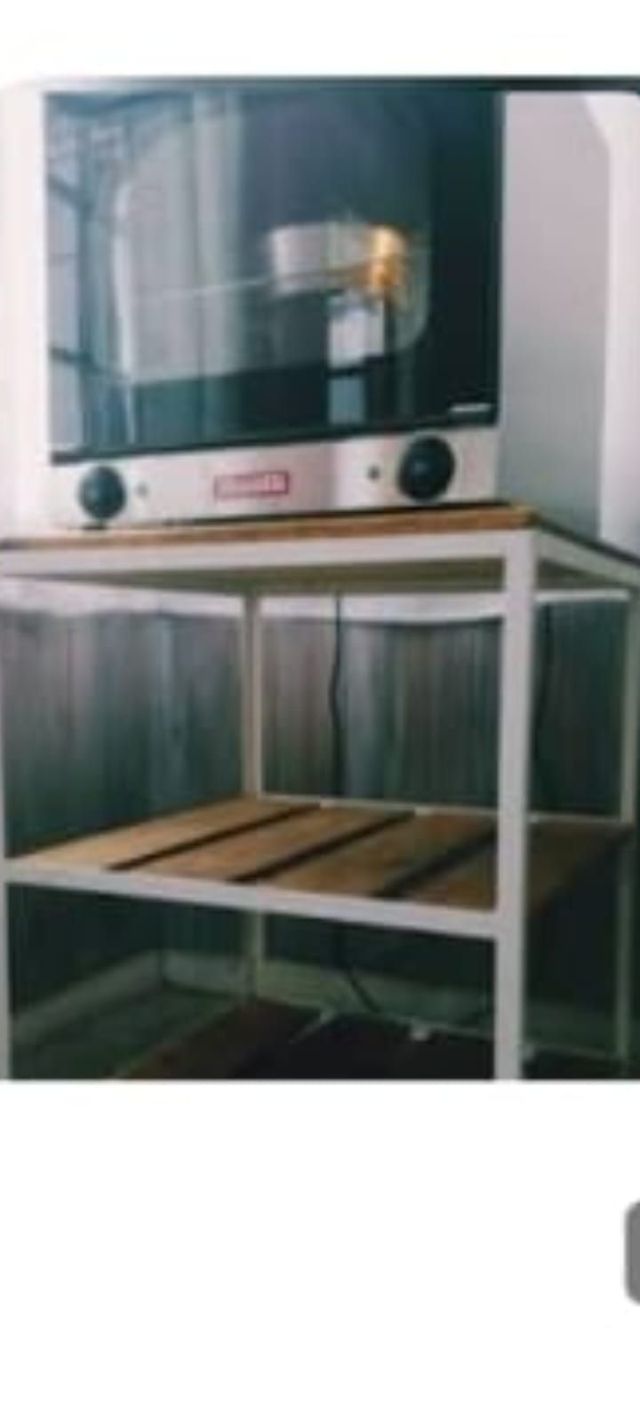 Encimera de cocina con horno microondas sobre un estante de madera y marco blanco.