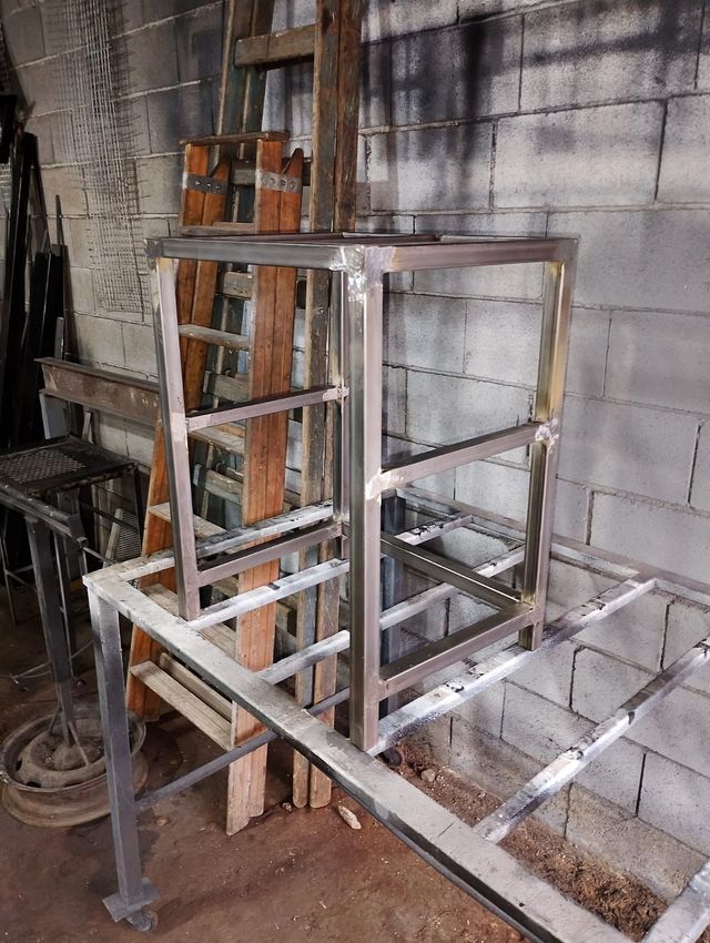Estructura metálica de andamio junto a una escalera en una habitación industrial sin terminar con paredes de hormigón.