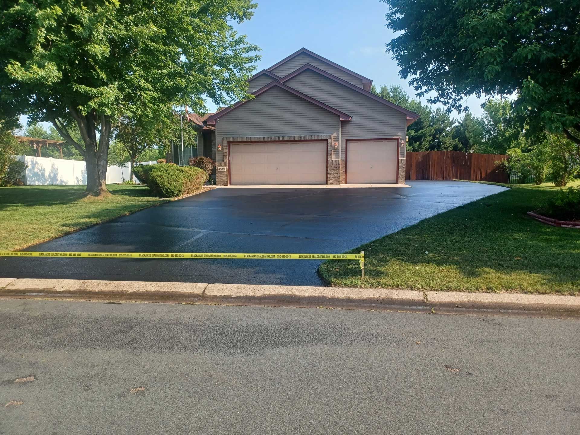 Suburban house with a wide driveway, two-car garage, and trees lining the lawn
