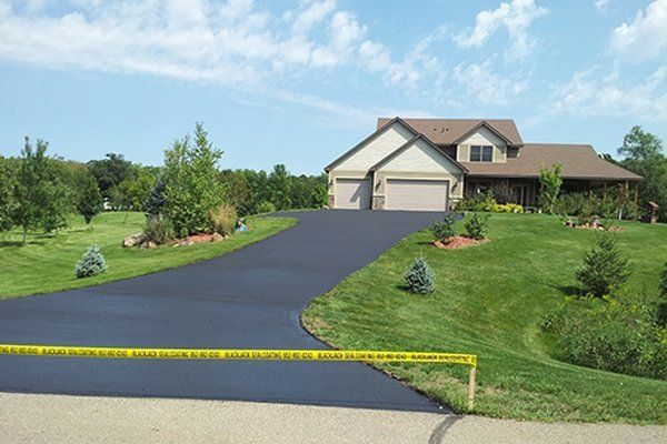 Coating Services — Anoka, MN — Black Jacks Sealcoating & Snow Removal Services A large house with a large driveway leading to it