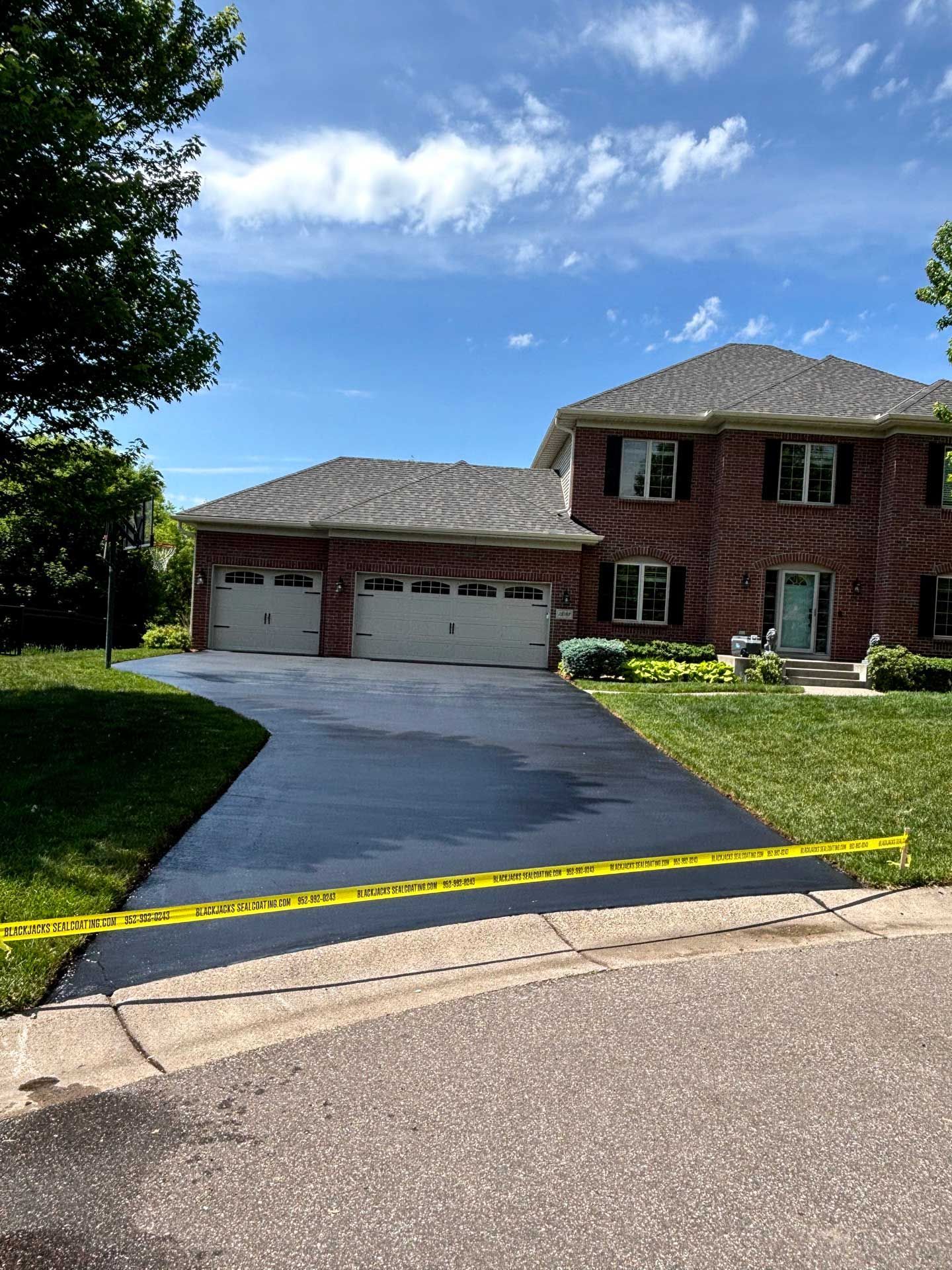 Suburban brick two-story house with double garage and driveway under a blue sky, taped off with yellow caution tape