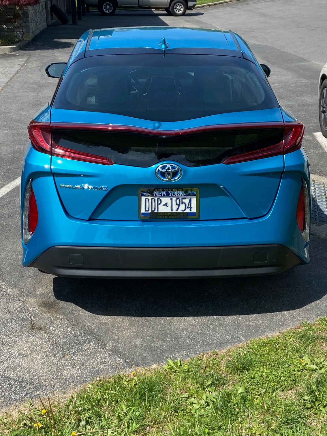 A blue Toyota Prius hybrid parked on asphalt seen from a rear-facing view.
