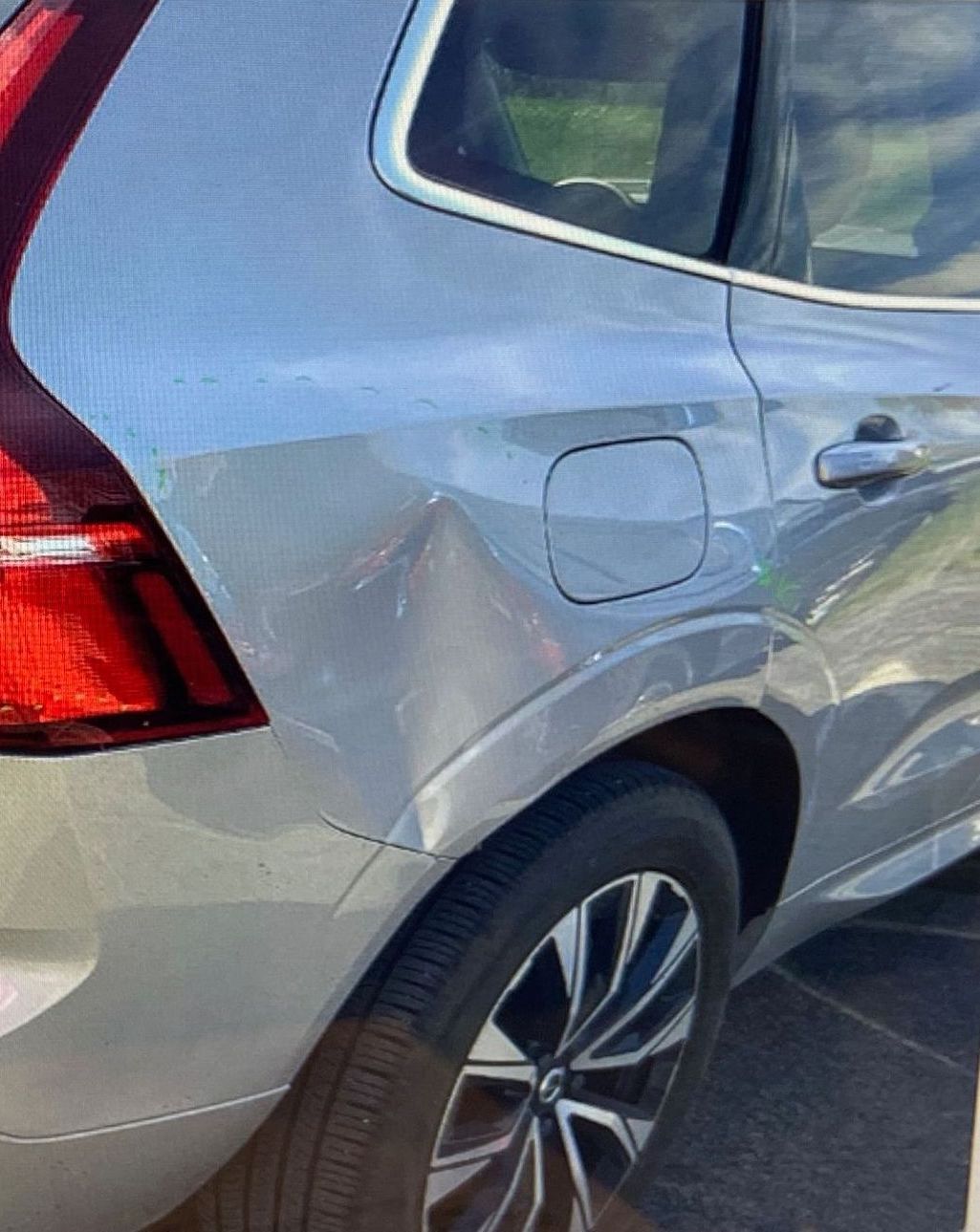 Silver Volvo SUV showing a dent in the rear quarter panel near the fuel door and taillight.