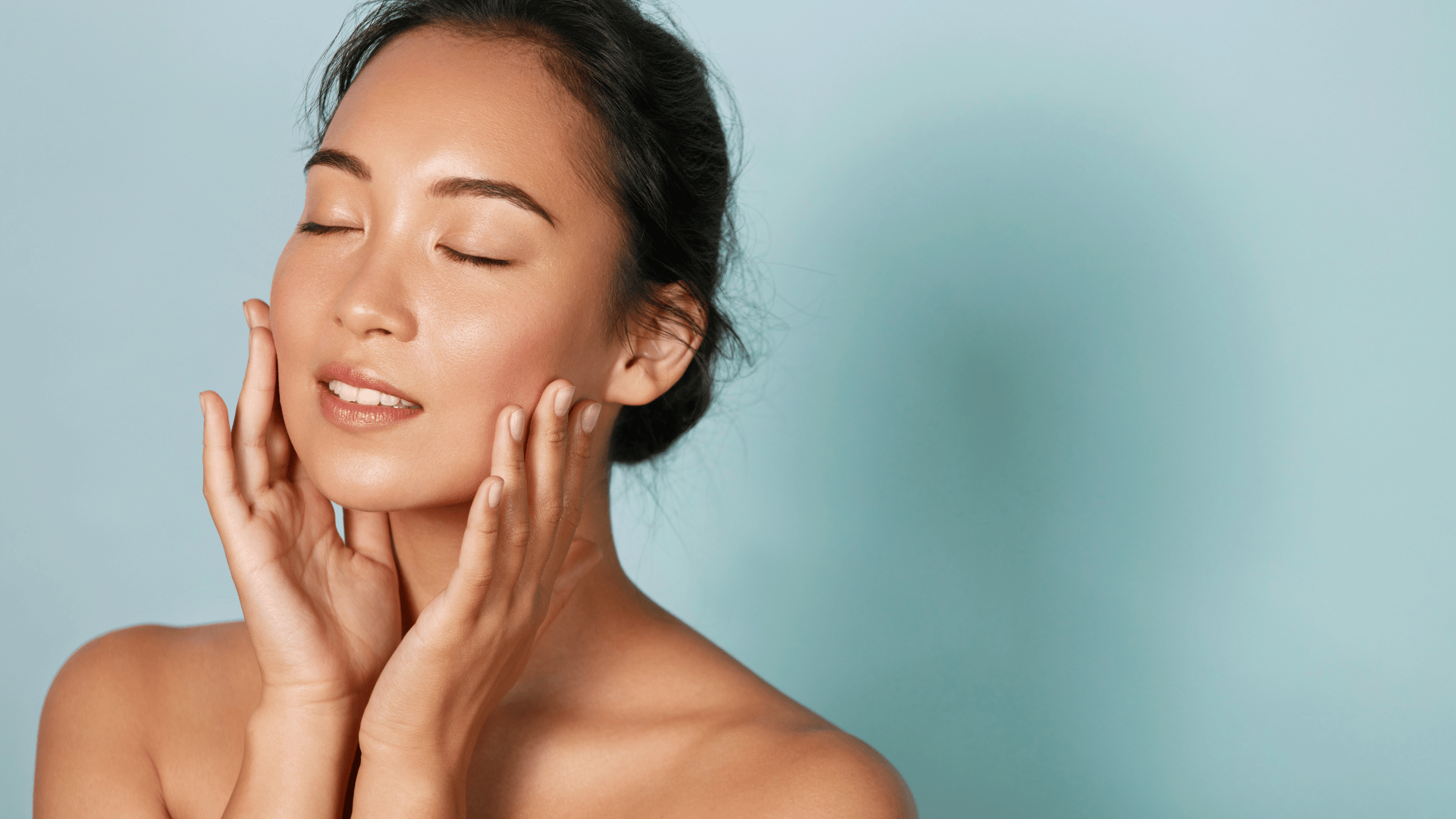 Woman applying skincare to her face against a light blue background
