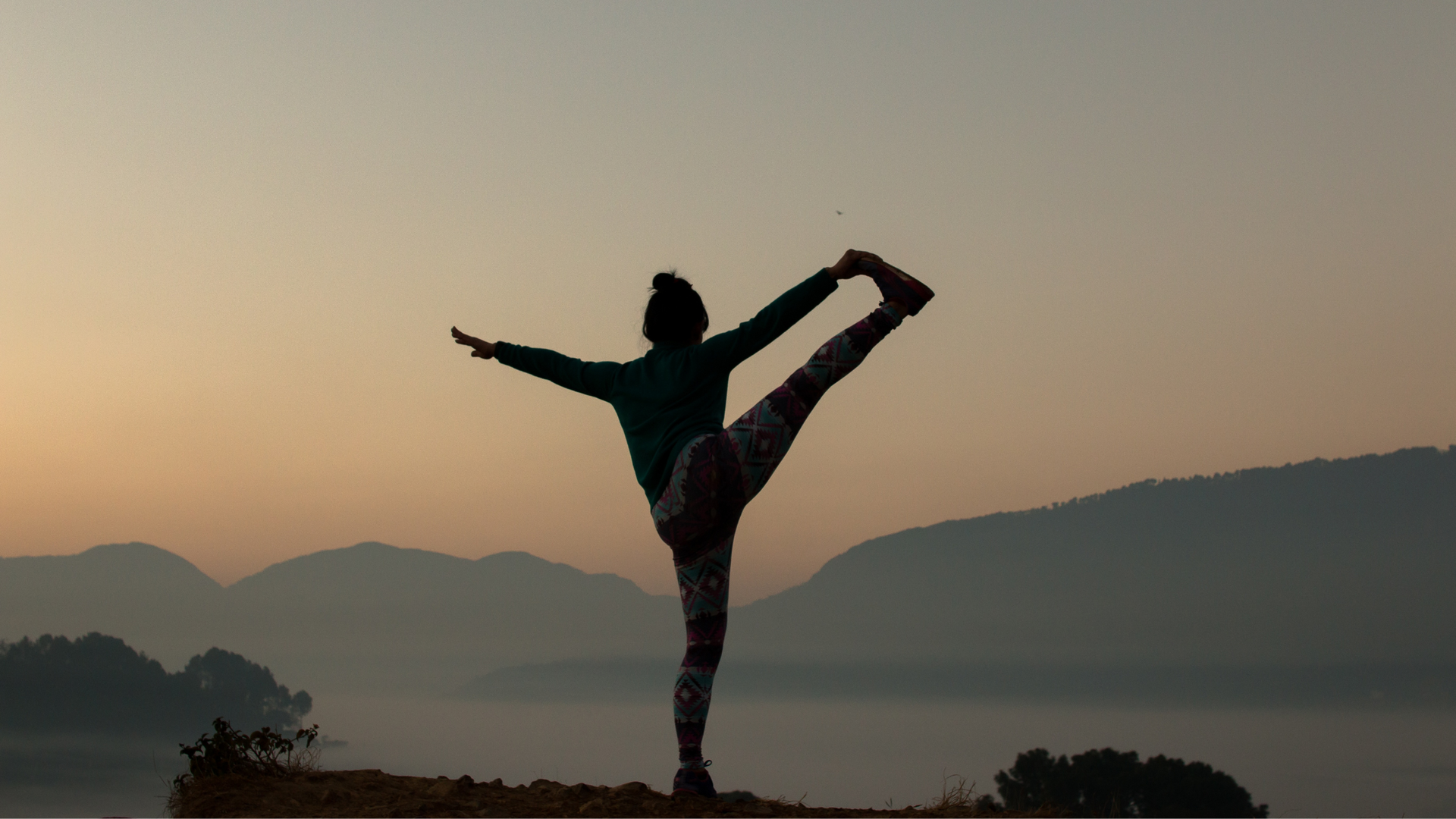 woman stretching on top of a mountain