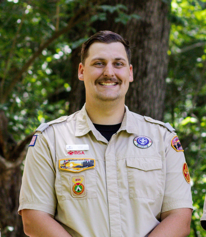 A man in a boy scout uniform is smiling for the camera