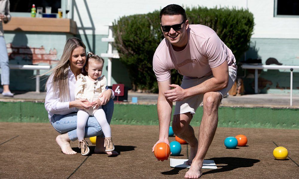 a young family enjoying a game of barefoot bowls at Albion Park Bowling Club
