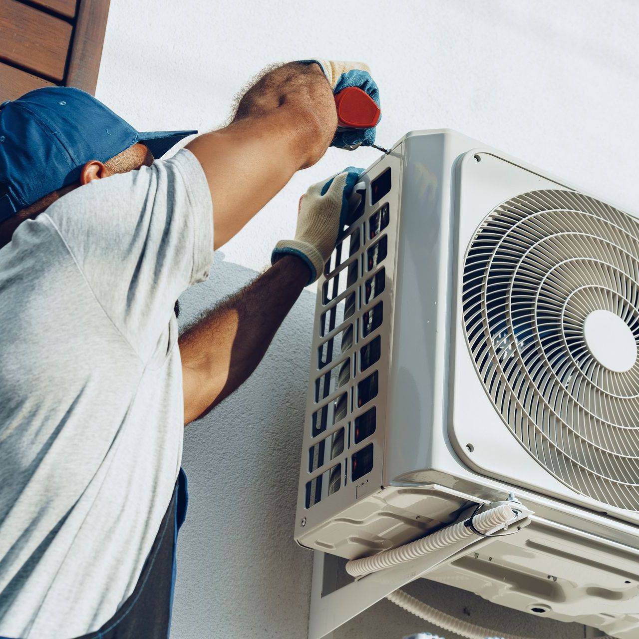 a man is fixing an air conditioner on the side of a building .