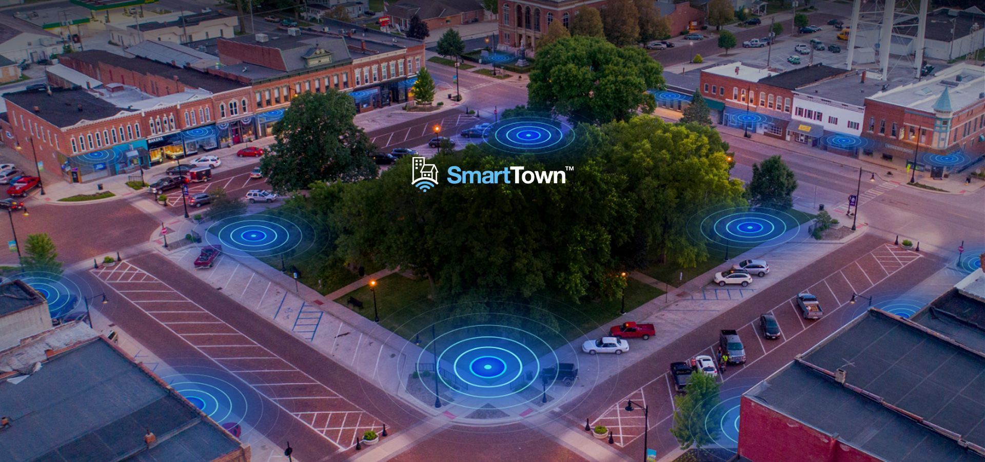 SmartTown Wi-Fi An aerial view of a city at night with a smart town logo in the middle of the street.