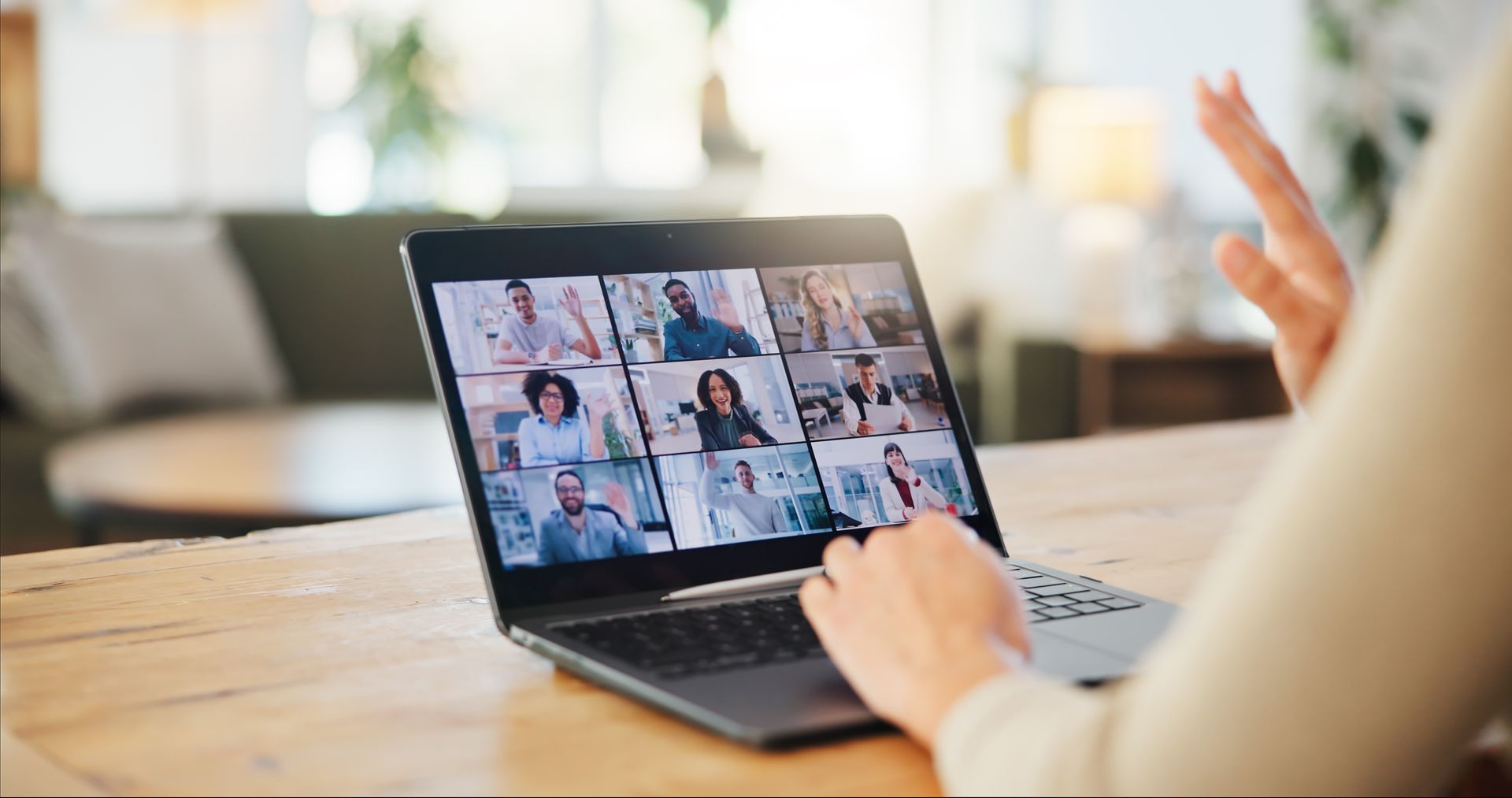 Person on a laptop in a video conference, with multiple participants visible on screen.