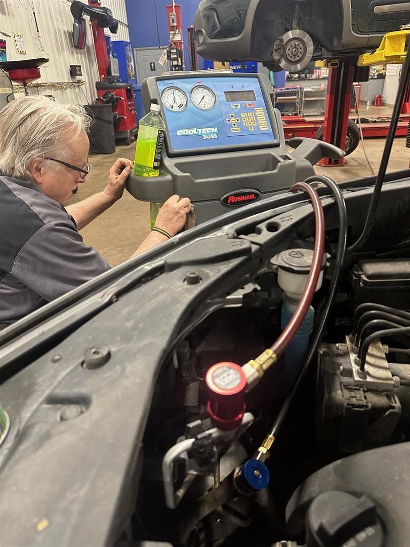 A man is working on a car in a garage. | Lou's Car Care Center, Inc.