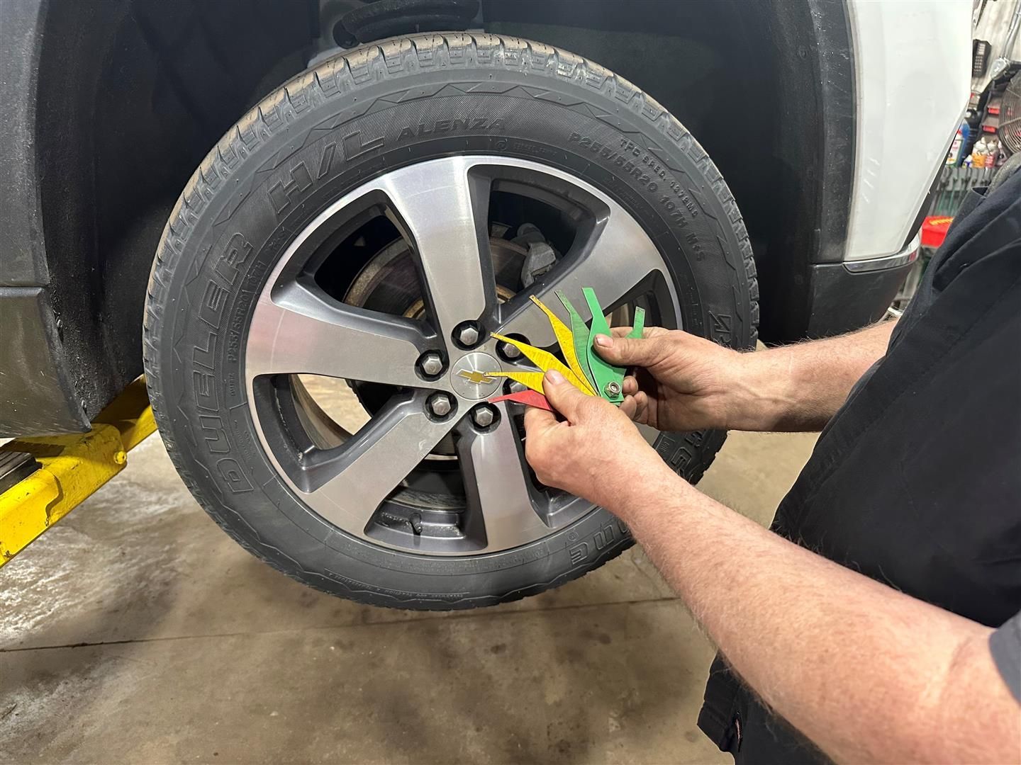 A man is adjusting a tire on a car. | Lou's Car Care  Center Inc.