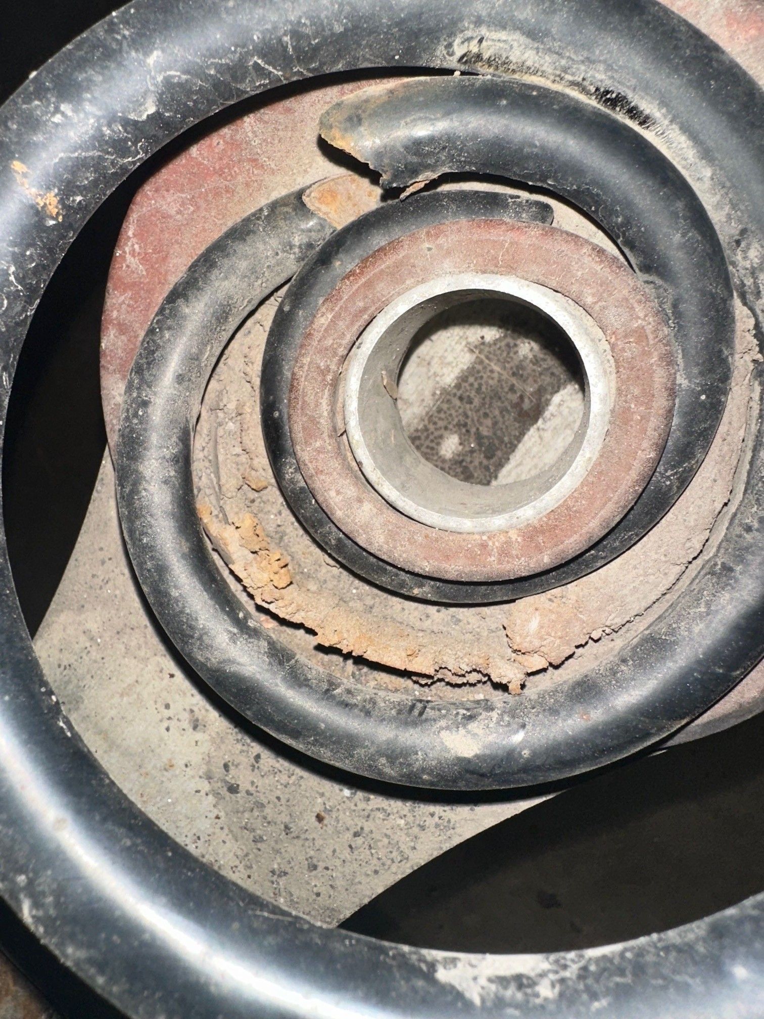 A broken, black coild spring with rust on a vehicle. | Lou's Car Care Center, Inc.