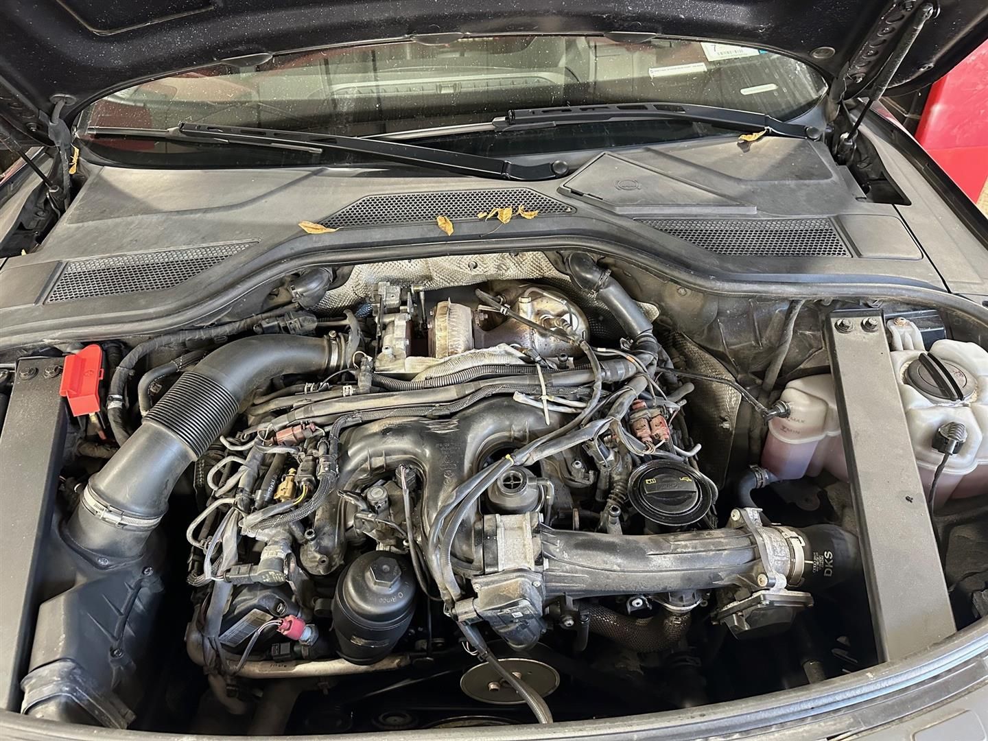 The engine of a car is shown with the hood open. | Lou's Car Care Center, Inc.